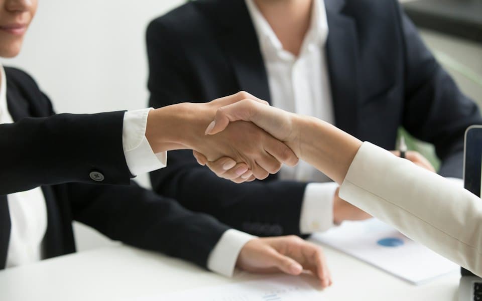 Two people shaking hands over a finance deal